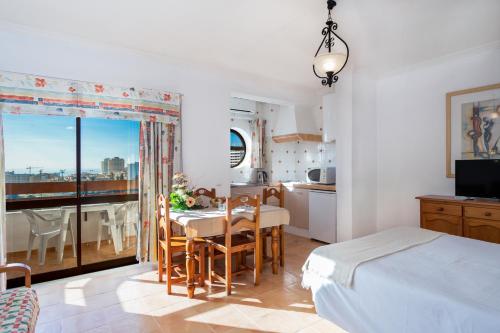 波尔蒂芒Mirachoro Portimao的一间卧室配有一张床铺和一张桌子,还设有一间厨房
