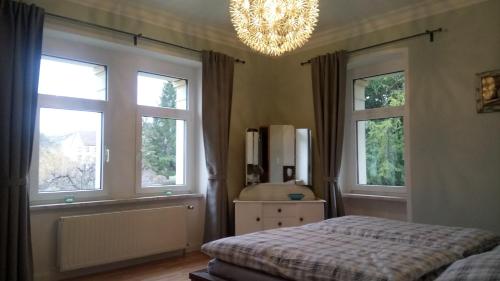 塔勒Villa Heimburg的一间卧室配有一张床、两个窗户和吊灯