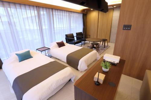 那霸Tabinoteitaku Okinawa Naha的酒店客房设有两张床和一张桌子。