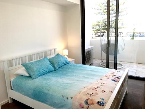 凯阿玛Kiama Executive的一间卧室配有一张带蓝色枕头的床和一扇窗户。