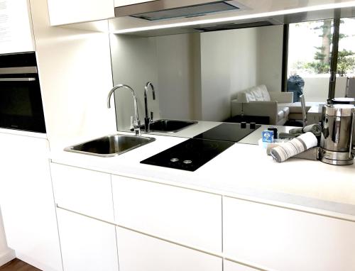 凯阿玛Kiama Executive的白色的厨房设有水槽和炉灶。