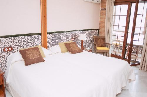 圭哈尔谢拉Vivienda Turistica Arabeluj的一间带白色床的卧室和一个阳台