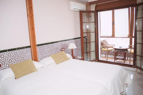 圭哈尔谢拉Vivienda Turistica Arabeluj的一间带白色床的卧室和一个阳台