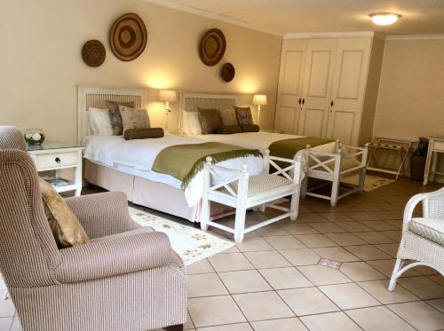 乔治Malvern Manor Country Guest House的一间卧室配有两张床、一张沙发和椅子