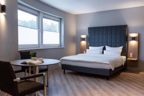 拉姆斯泰因-米森巴赫圆环酒店的一间卧室配有一张床、一张桌子和两个窗户