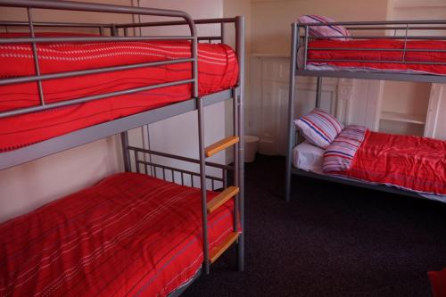 赫克瑟姆Newbrough Bunkhouse的一间客房配有三张双层床和红色床单。