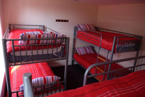 赫克瑟姆Newbrough Bunkhouse的带红色床单的客房内的三张双层床