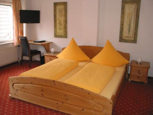 Mühlheim an der DonauHotel Gästehaus Theresia Garni的一间卧室配有一张带黄色枕头的木床