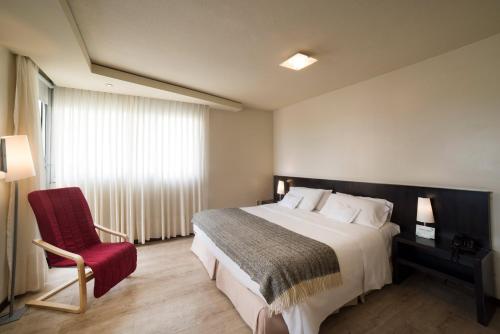 蒙得维的亚27 Suites Hotel的一间卧室配有一张大床和一张红色椅子