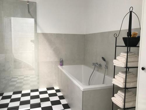 海牙B&B Valkenbos的一间带浴缸和淋浴的浴室,铺有 ⁇ 格地板