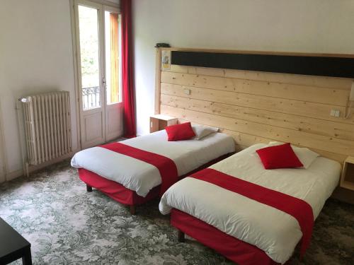 巴涅尔-德吕雄小火车公寓式酒店的一间设有两张红色和白色床单的房间