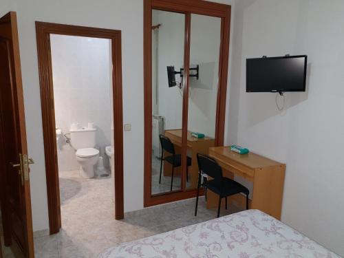 马德里安吉丽纳旅馆的一间卧室配有一张床、一张书桌和一面镜子