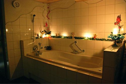 巴特欣德朗Ferienhof Ammann的带浴缸的瓷砖浴室设有照明灯。