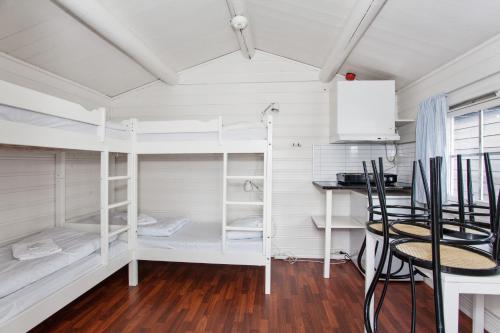 卑尔根Midttun Motell & Camping AS的客房设有白色双层床和桌椅。