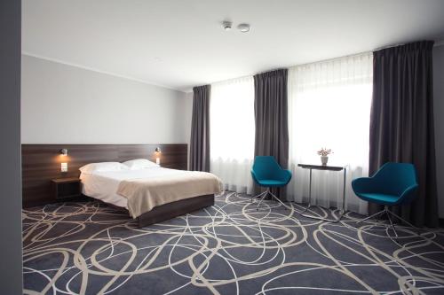 奥古斯图Hotel Nad Nettą的酒店客房,配有一张床和两张蓝色椅子
