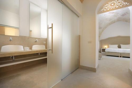 莱韦拉诺Masseria Donna Huga的一间带两个盥洗盆的浴室和一张位于客房内的床。