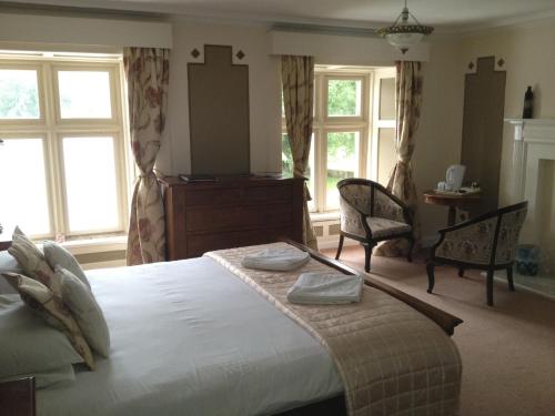 AlwintonClennell Hall Country House - Near Rothbury - Northumberland的一间卧室配有一张大床、两把椅子和窗户。