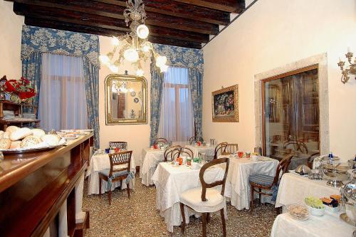 威尼斯帕拉佐欧多尼酒店的一间用餐室,配有2张带白色桌布的桌子