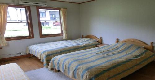 南鱼沼市Pension Come Relaxing Western-style room- Vacation STAY 14977的带2扇窗户的客房内的2张床