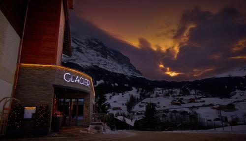 格林德尔瓦尔德冰川精品酒店 的雪覆盖的山前有标志的建筑