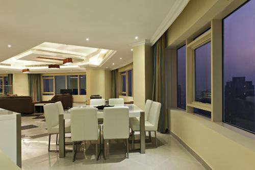多哈Magnum Hotel & Suites West Bay的一间带桌子和白色椅子的用餐室