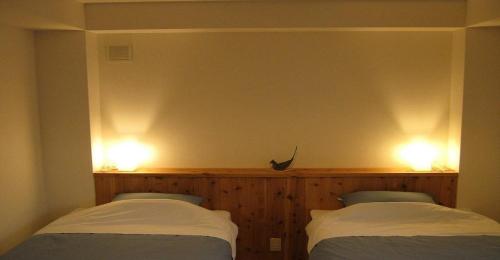 京都Guesthouse Hyakumanben Cross twin room / Vacation STAY 15395的两张床位于带两盏灯的墙上。