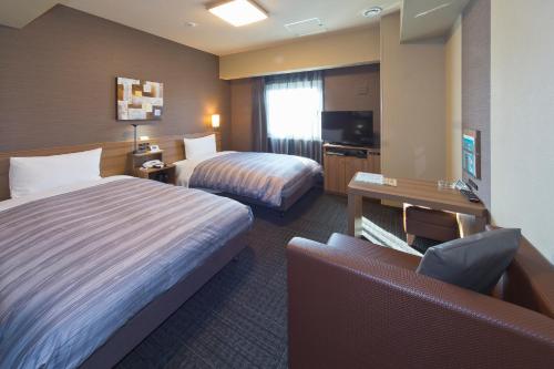 山口Hotel Route-inn Yamaguchi Yuda Onsen的酒店客房,设有两张床和一张沙发