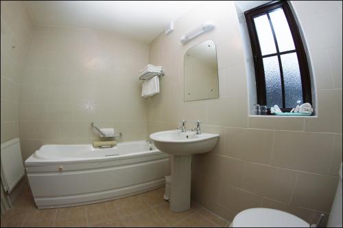克利夫登全双旅馆的一间带水槽、浴缸和卫生间的浴室