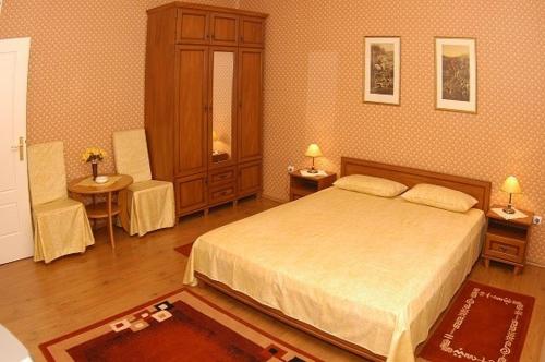 德布勒森Peron Panzió的一间卧室配有一张床和两张桌子及两张椅子