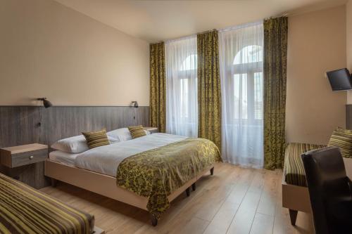 布拉格布拉格市中心广场酒店的酒店客房,配有一张床和两把椅子