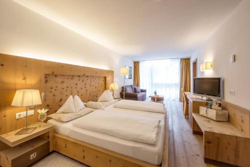 拉维拉Alpine Hotel Ciasa Lara的酒店客房设有一张大床和一台电视。