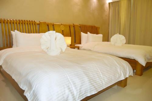 布赖代Yara Suites的一间卧室配有两张带白色床单的床