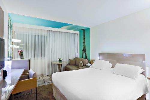 巴黎巴黎十五区凡尔赛门美居酒店的卧室配有一张白色大床和一把椅子
