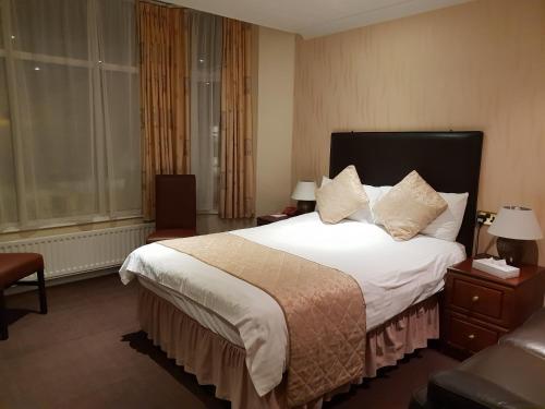 道格拉斯阿斯科特酒店的酒店客房配有一张带白色床单和枕头的大床。