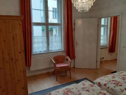 波茨坦Ferienwohnung Am Nauener Tor的一间卧室配有一张床、一把椅子和窗户。