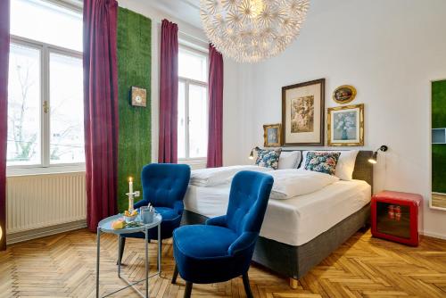 维也纳Leuhusen Collection Vienna的一间卧室配有一张床和两张蓝色椅子