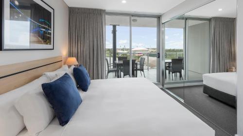 阿德莱德Oaks Adelaide Embassy Suites的酒店客房设有一张大床和一个阳台。