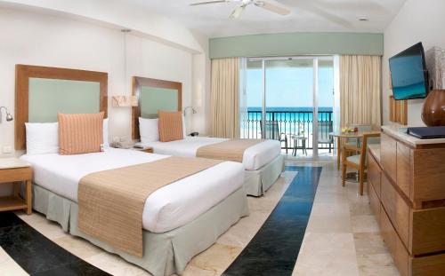 坎昆Grand Park Royal Cancun - All Inclusive的酒店客房设有两张床和电视。