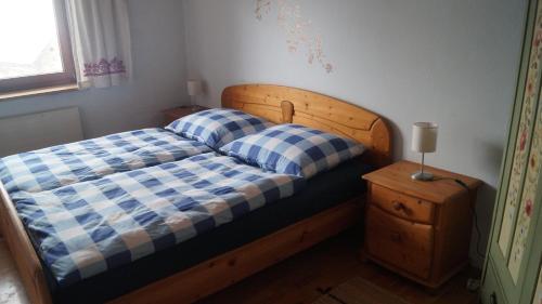 芬肯施泰因Ferienwohnung auf einem richtigen Bauernhof的一张带蓝白 ⁇ 面毯和床头柜的床