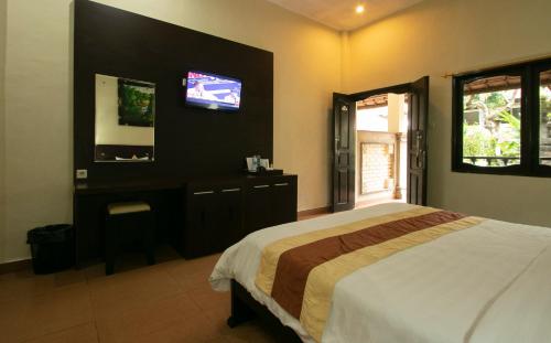 库塔巴厘岛桑迪度假酒店的卧室配有一张床,墙上配有电视。