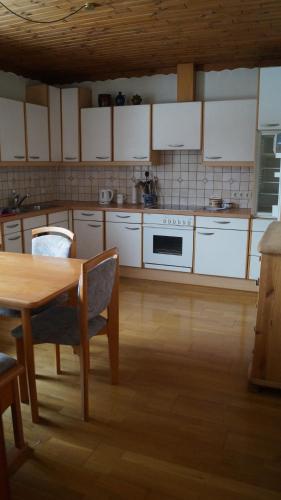 芬肯施泰因Ferienwohnung auf einem richtigen Bauernhof的厨房配有白色橱柜、桌子和炉灶。
