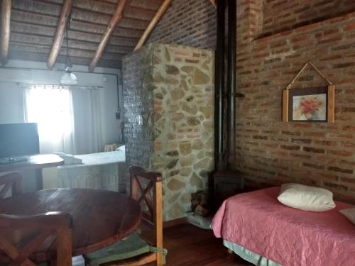 科隆Cabañas del Uru的一间设有砖墙、一张桌子和一张床的房间