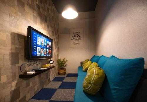 哥打京那巴鲁Vibrant Hostel的客厅配有蓝色的沙发和平面电视。