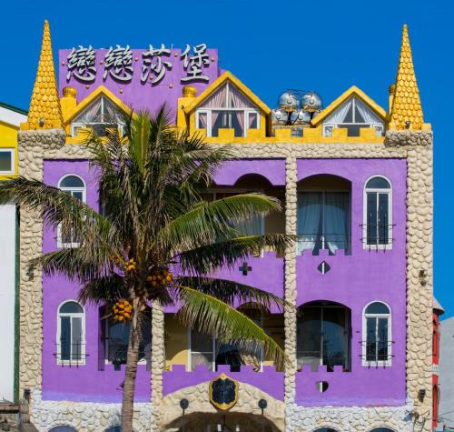 鹅銮鼻墾丁戀戀莎堡特色民宿 Castillo的一座紫色的建筑,前面有棕榈树