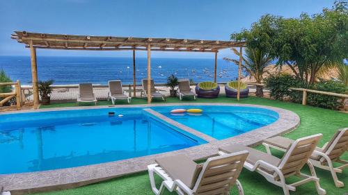 洛斯拉甘斯艾尔格兰维洛酒店的一个带椅子的游泳池,背景是大海