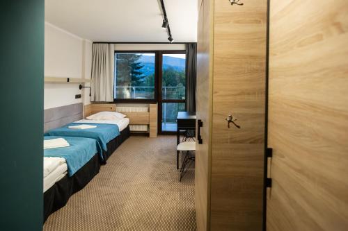 什切尔克Hotel Halo Szczyrk的酒店客房设有两张床和窗户。
