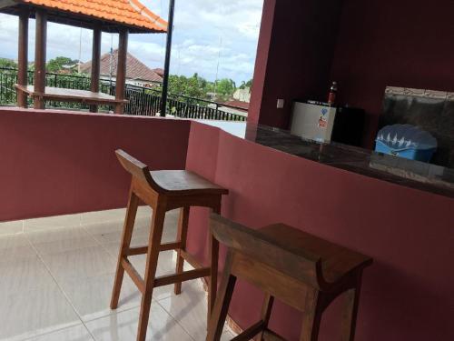 金巴兰德思德考斯特巴厘岛民宿的吧台上摆放着两把木凳