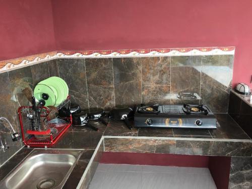 金巴兰德思德考斯特巴厘岛民宿的厨房柜台设有水槽和炉灶。