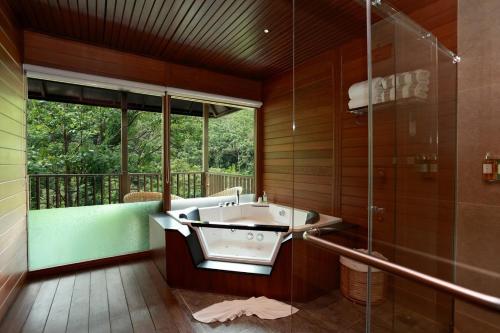 马迪凯里The IBNII - Eco Luxury Resort的带浴缸和玻璃淋浴间的浴室。