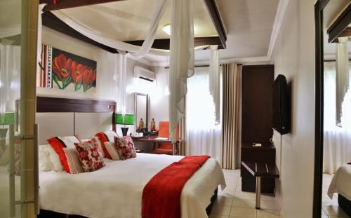 恩潘盖尼BON Hotel Empangeni的一间卧室配有一张带红色和白色枕头的大床